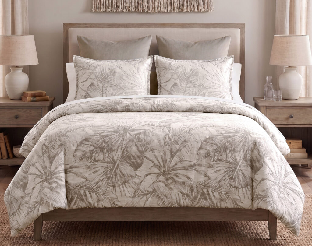 Neutral-toned bedroom with palm-patterned comforter and pillows on a wooden bed frame, flanked by lamps.