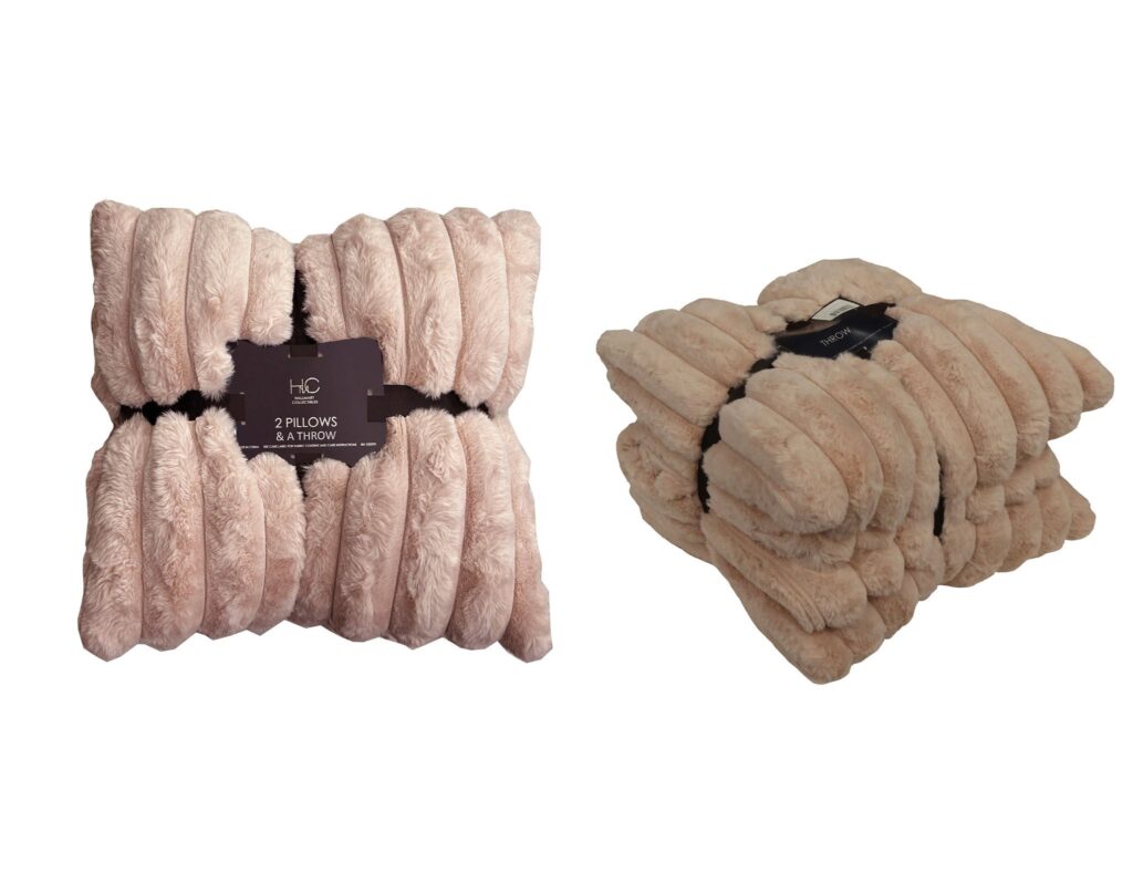 Two fluffy blush-pink plush pillows with a coordinating faux-fur throw; product tag visible on the left.