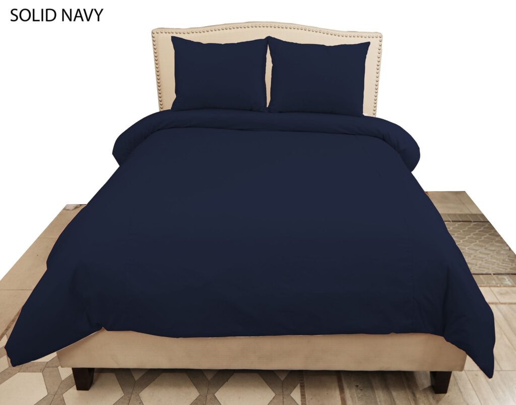 Bed with navy solid bedding and two navy pillows, beige nailhead-trim headboard, and 'SOLID NAVY' text at the top left.